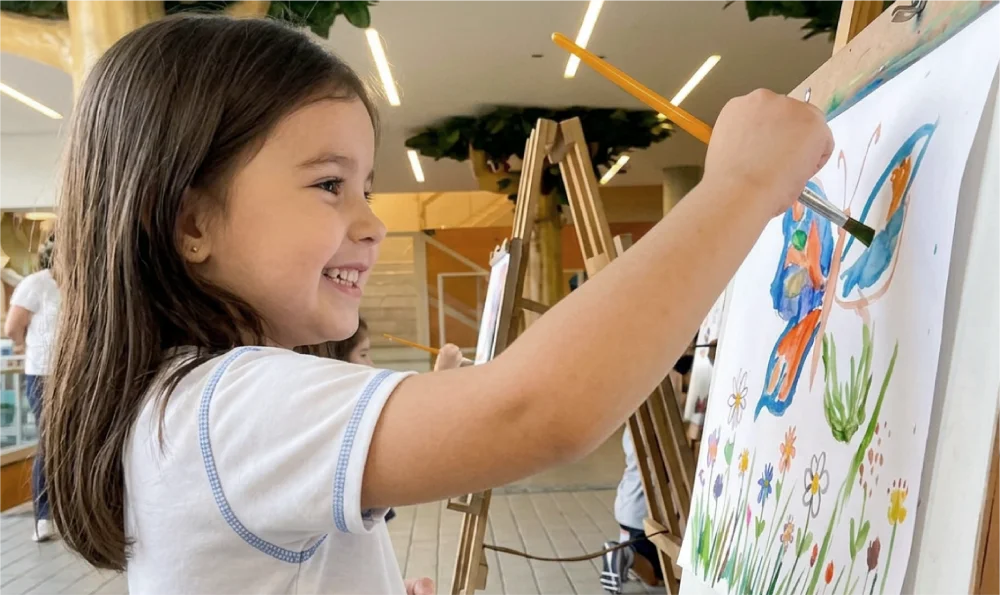 Aluna pintando em um cavalete no Colégio Ábaco